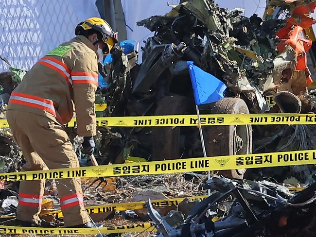 A firefighter works near a wrecked landing gear (R) at the scene where a Jeju Air Boeing 737-800 series aircraft crashed and burst into flames at Muan International Airport in Muan, some 288 kilometres southwest of Seoul on December 31, 2024. The Boeing 737-800 was carrying 181 people from Thailand to South Korea when it crashed on arrival on December 29, killing everyone aboard -- save two flight attendants pulled from the twisted wreckage of the worst aviation disaster on South Korean soil. (Photo by YONHAP / AFP) / - South Korea OUT / NO ARCHIVES -  RESTRICTED TO SUBSCRIPTION USE