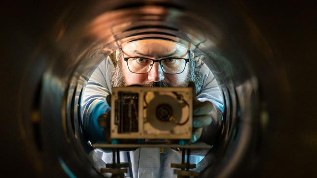 Dr Paddy Neumann looking down the barrel of a vacuum chamber with the Neumann Drive inside.