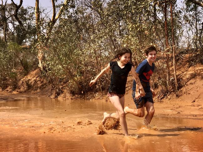 Jake Finch, 12, and Zahli Finch, 10, playing in the rain water at Stephens Creek, Broken Hill. Picture: Kelly Finch