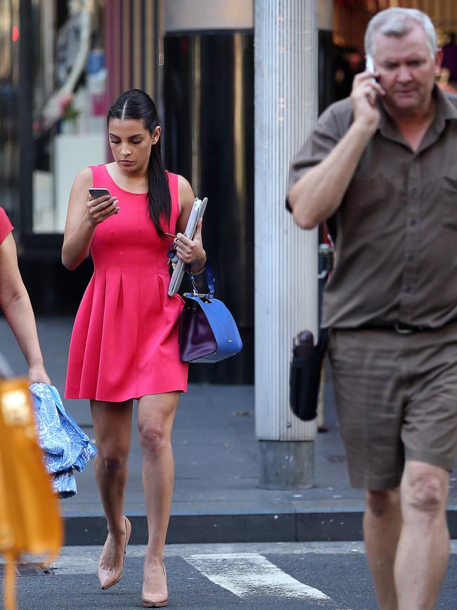 Pedestrians in Sydney using their phones as they cross a city street.