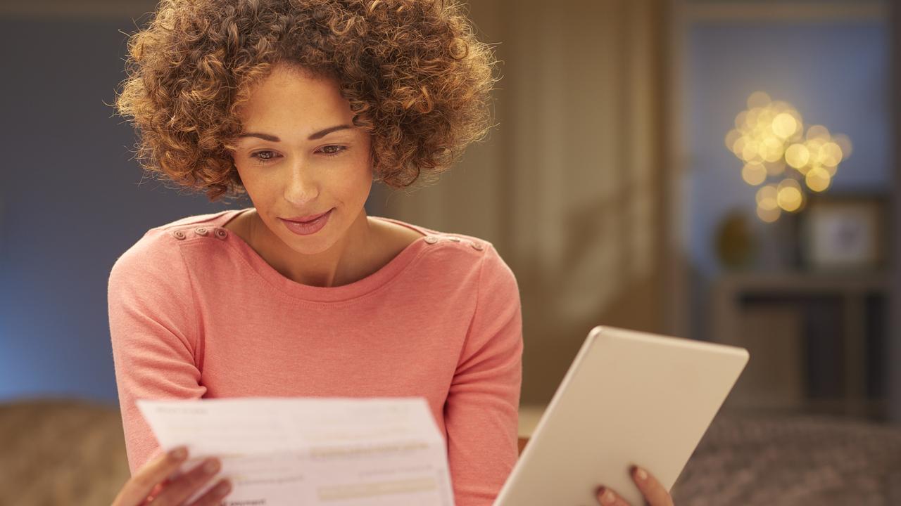 A woman at home look at her bills and holding an iPad while reviewing her home loan. Picture: iStock.