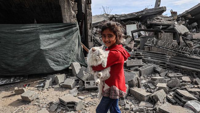 A Palestinian child carries a cat in the rubble of damaged buildings following Israeli bombardment in Rafah, on the southern Gaza Strip on February 12, 2024. Picture: Said Khatib/AFP