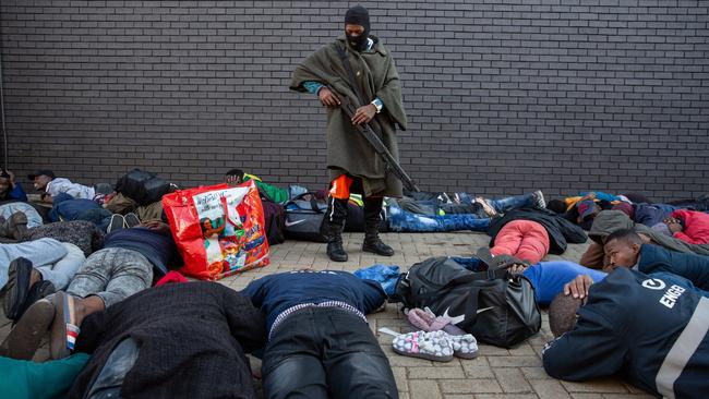 A police officer guards suspected looters at a shopping centre in Johannesburg. Picture: Getty Images.