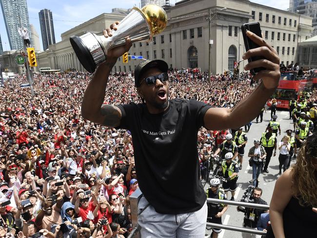 Toronto Raptors forward Kawhi Leonard takes a selfie holding his playoffs MVP trophy during the NBA basketball championship team's victory parade in Toronto, Monday, June 17, 2019. (Frank Gunn/The Canadian Press via AP)