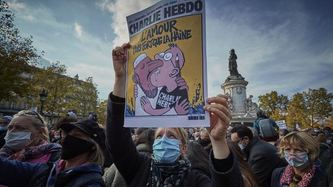 Protesters hold copies of the satirical newspaper Charlie Hebdo during an anti-terrorism vigil at Place de La Republique for the murdered school teacher Samuel Paty.