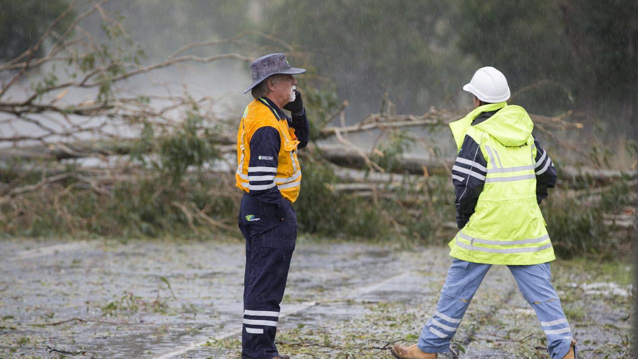 Energex workers tend to fallen trees across a road after a super cell storm tore through Long Flat south of Gympie. Photo Lachie Millard