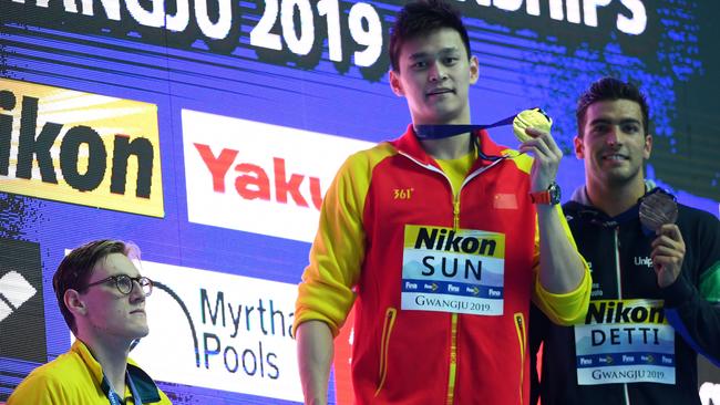 GWANGJU, SOUTH KOREA – JULY 21: Silver medallist Mack Horton of Australia (L) watches as gold medallist Sun Yang of China hold up his medal, with bronze medallist Gabriele Detti of Italy (R) during the medal ceremony for Men's 400m Freestyle Final on day one of the Gwangju 2019 FINA World Championships at Nambu International Aquatics Centre on July 21, 2019 in Gwangju, South Korea. (Photo by Quinn Rooney/Getty Images)