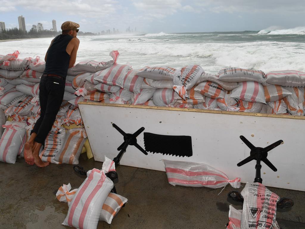 Rick Shores Restaurant staff member Mario Wanagat is seen sandbagging the front of the restaurant in an attempt to protect it from the oncoming waves at Burleigh Heads on the Gold Coast. Picture: Darren England/AAP