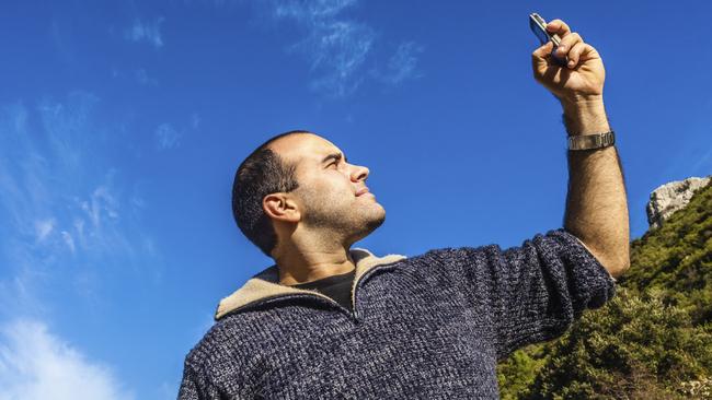 a man trying to pick up the signal on his mobile phone