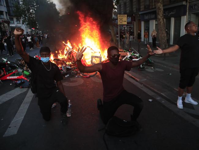 Protesters kneel and react by a burning barricade during a demonstration in Paris. Picture: Michel Euler