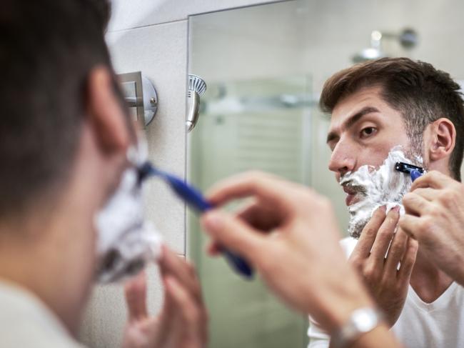 Man shaving in front of the mirror in his bathroom