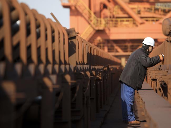 A dock worker inspects a conveyer belt at an iron-ore transfer and storage center operated by the Shanghai International Port Group in Shanghai. Picture: Qilai Shen/Bloomberg.