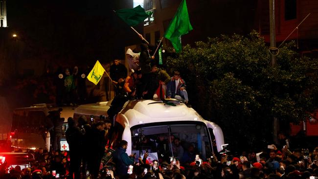 Palestinian men waving Hamas (green) and Hezbollah (yellow) flags sit on top of a Red Cross bus carrying released prisoners from Ofer military prison in the West Bank. Picture: AFP.