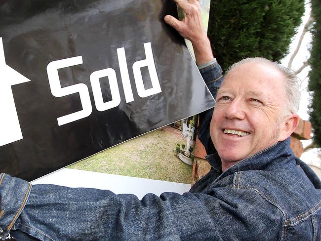 Vendor Andrew Carlton sticks on the sold sign after the auction of 8 Pilrig Avenue Newtown