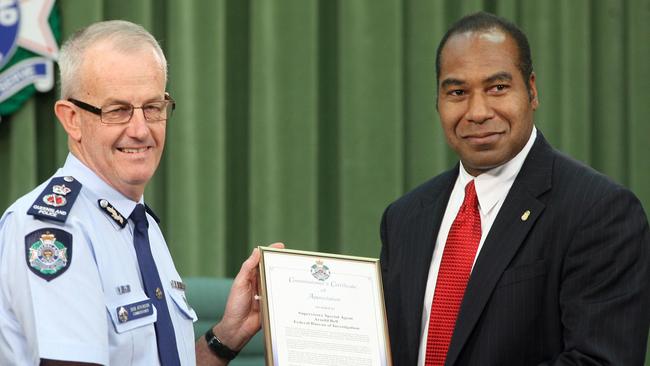 Then police commissioner Bob Atkinson presents a certificate of appreciation to Special FBI agent Arnold Bell for his role in Operation Achilles.