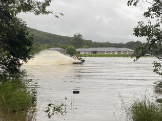 People on a jetski in front of flooded property opposite Treetops Adventure Park on the NSW Central Coast. Picture: Dana Pendrick