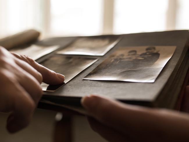 Close up unrecognizable person looking photo album pointing to one photo