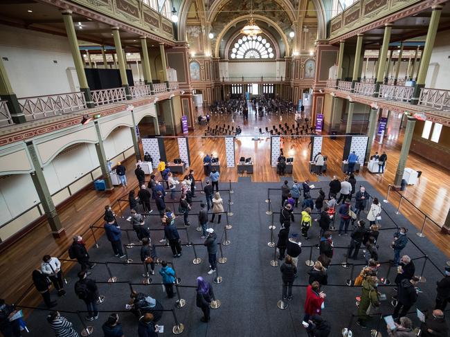 MELBOURNE, AUSTRALIA - MAY 28: People wait to be register their information before being vaccinated  at the Royal Exhibition Building COVID-19 Vaccination Centre on May 28, 2021 in Melbourne, Australia. All Victorians aged 40 and over are eligible to receive either the Pfizer or AstraZeneca COVID-19 vaccines as the Commonwealth COVID-19 vaccination program expands in the state. The vaccine program expansion comes as Victoria enters its first day of a seven-day lockdown following a COVID-19 cluster outbreak in Melbourne's northern suburbs. From midnight, all Victorian residents are subject to stay home orders, and are only allowed to leave home for five reasons: care and caregiving, exercise, work and to buy groceries, or to get vaccinated. The lockdown is effective from 11:59 pm Thursday 27 May to 11:59 pm Thursday 3 June 2021. (Photo by Darrian Traynor/Getty Images) *** BESTPIX ***