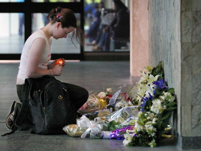 A studnet lights a candle at flowers left in memory of the students killed and injured. Picture: Craig Borrow