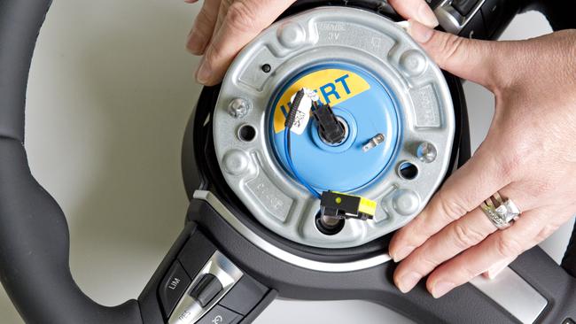 A worker demonstrates a pyroelectric wheel airbag initiator during a presentation for journalists at Takata in 2014. Picture: AP