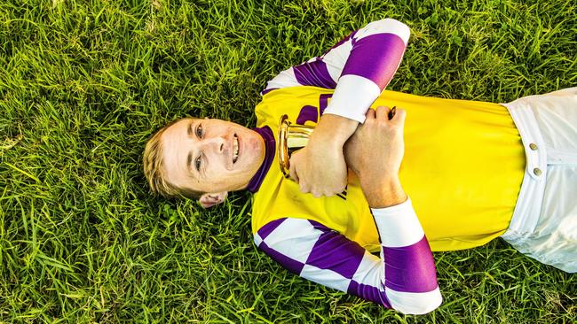 Jockey Ben Looker lies down on his home Grafton turf after winning the Grafton Cup on Sacred Day