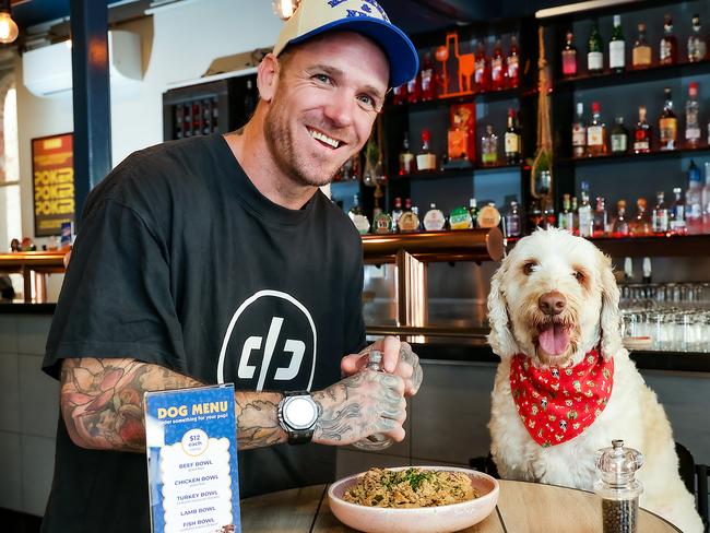 Former Collingwood footballer  Dane Swan is putting dog food on his pub menu (for dogs) this December. Dane is pictured with Larry the dog and his food at The Union Hotel in Windsor. Picture: Ian Currie