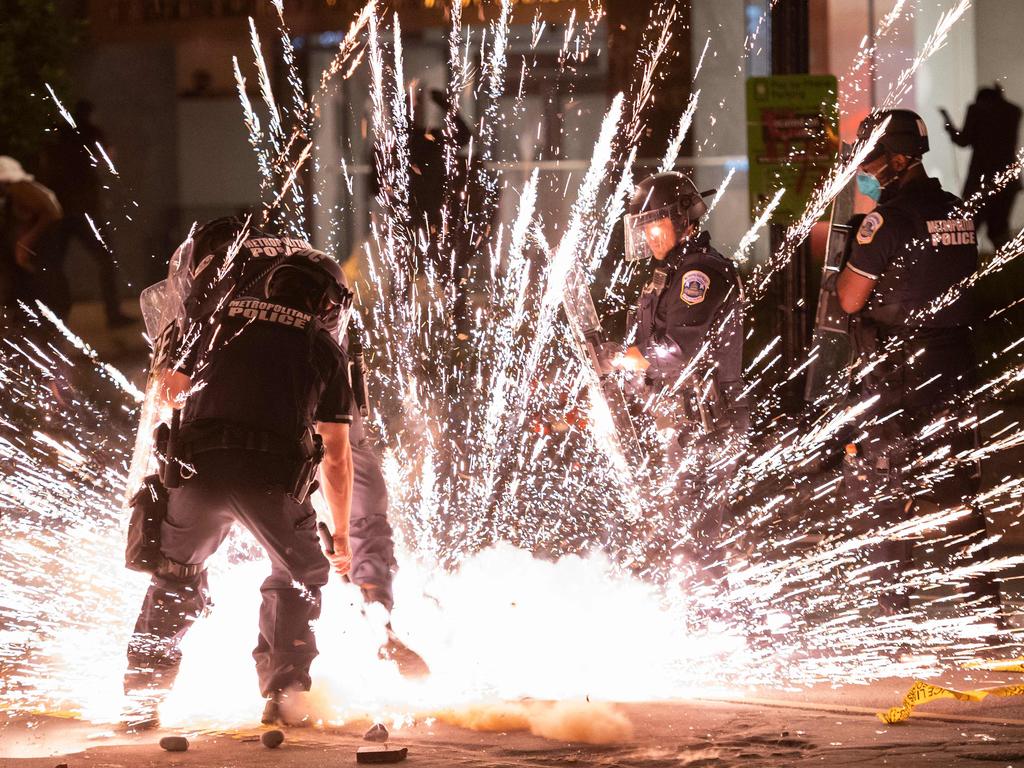 A firecracker thrown by protesters explodes under police one block from the White House in Washington DC. Picture: Andrew Caballero-Reynolds/AFP