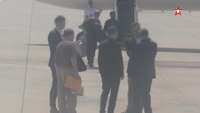 Two men in suits (right) shook hands while Reed entered the US plane behind them and Yaroshenko waited to the left before being escorted to a plane behind the camera.