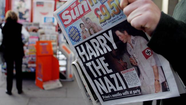 A man reads the newspaper "The Sun" in London with a headline about Prince Harry wearing a Nazi uniform at a costume party in 2005.