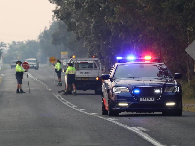 Police are seen as bushfires burn in Yamba, NSW, Monday, September 9, 2019. Firefighters across NSW remain on edge as several bushfires burn out of control in the state's north, with authorities issuing an emergency warning for a fire burning across almost 7000 hectares at Shark Creek. (AAP Image/Jason O'Brien)