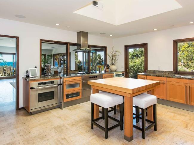 The kitchen is fit with a stainless steel oven, granite surfaces and a simple square table sitting centrally.