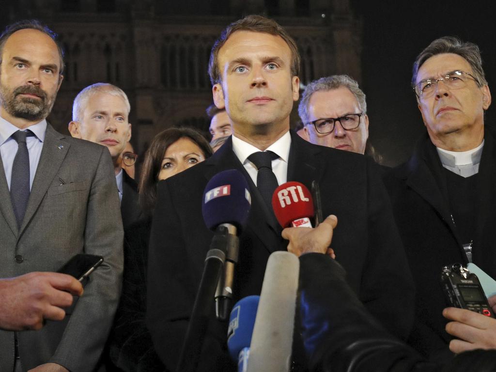 French Prime Minister Edouard Philippe, left, French President Emmanuel Macron, and Archbishop of Paris, Michel Aupetit, right, answer reporters after watching the fire. Picture: Philippe Wojazer/AP