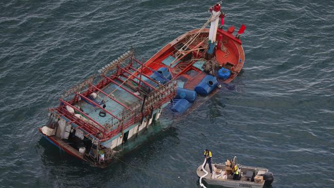 Workers attempt to stem the flow of diesel from a Vietnamese fishing boat.