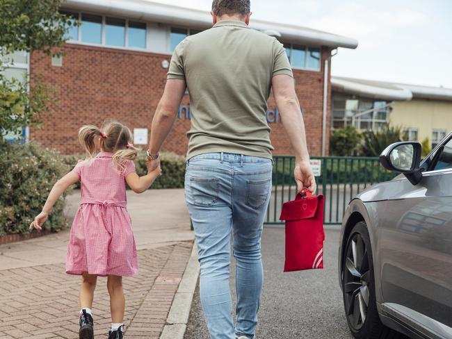 Close-up of a caucasian father walking his little girl into the school gates ready for her first day back. iStock