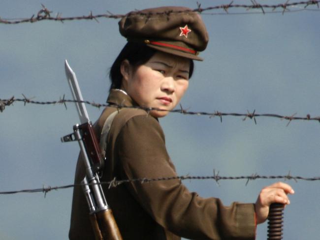 A female North Korean soldier looks out from behind a barbed wire fence around a camp on the North Korean river banks across from Hekou, northeastern China's Liaoning province. Picture: Ng Han Guan/AP