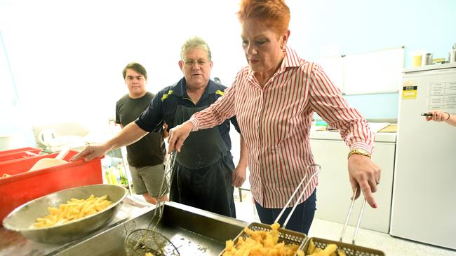 One Nation leader Pauline Hanson is seen cooking at a fish and chip shop after being invited in by owner Gary Bowen (left) during a stop on the One Nation 'Battler Bus' in Rockhampton on the 2017 Queensland election trail. Picture: Dave Hunt