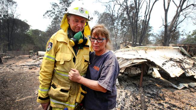 Kim Macdonald with her firefighter partner Gary Greene and the remains of their burnt out house in Bobin. Picture: Nathan Edwards