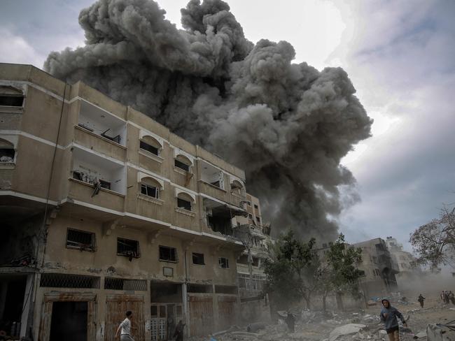 Palestinians rush for cover as smoke billows after Israeli bombardment in central Gaza City. Picture: AFP