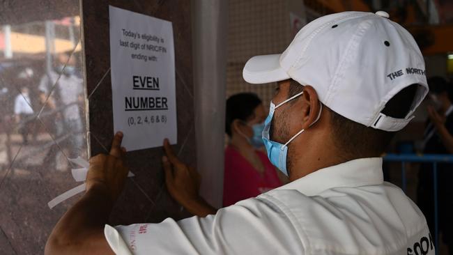 In Singapore, which has experienced a second wave of COVID-19 infections, a council employee posts an instruction notice on who can enter a wet market Picture: AFP