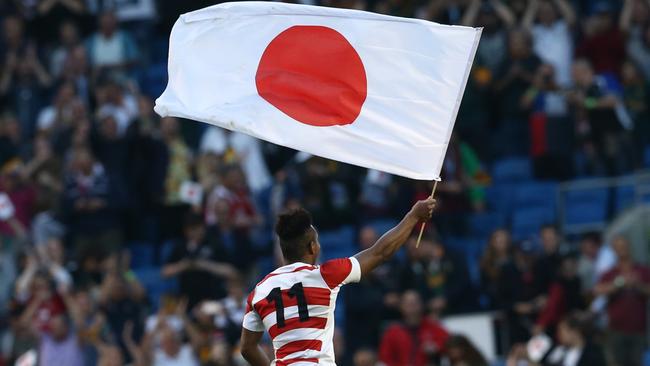 Japan's wing Kotaro Matsushima waves the Japanese national flag as the team celebrate their victory in the Pool B match of the 2015 Rugby World Cup between South Africa and Japan at the Brighton community stadium in Brighton, south east England on September 19, 2015. Japan won 34-32. AFP PHOTO / JUSTIN TALLIS  RESTRICTED TO EDITORIAL USE, NO USE IN LIVE MATCH TRACKING SERVICES, TO BE USED AS NON-SEQUENTIAL STILLS (Photo by JUSTIN TALLIS / AFP)