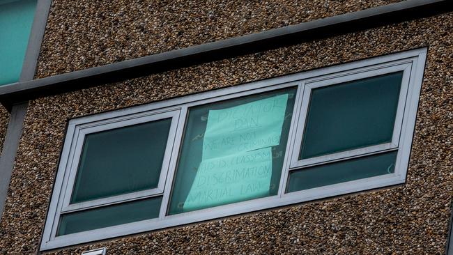 A sign is seen taped to a window of an apartment at a public housing flat in Flemington reading 'Dictator Dan we are not criminals! This is Classism Discrimination Martial law'. Picture: Getty