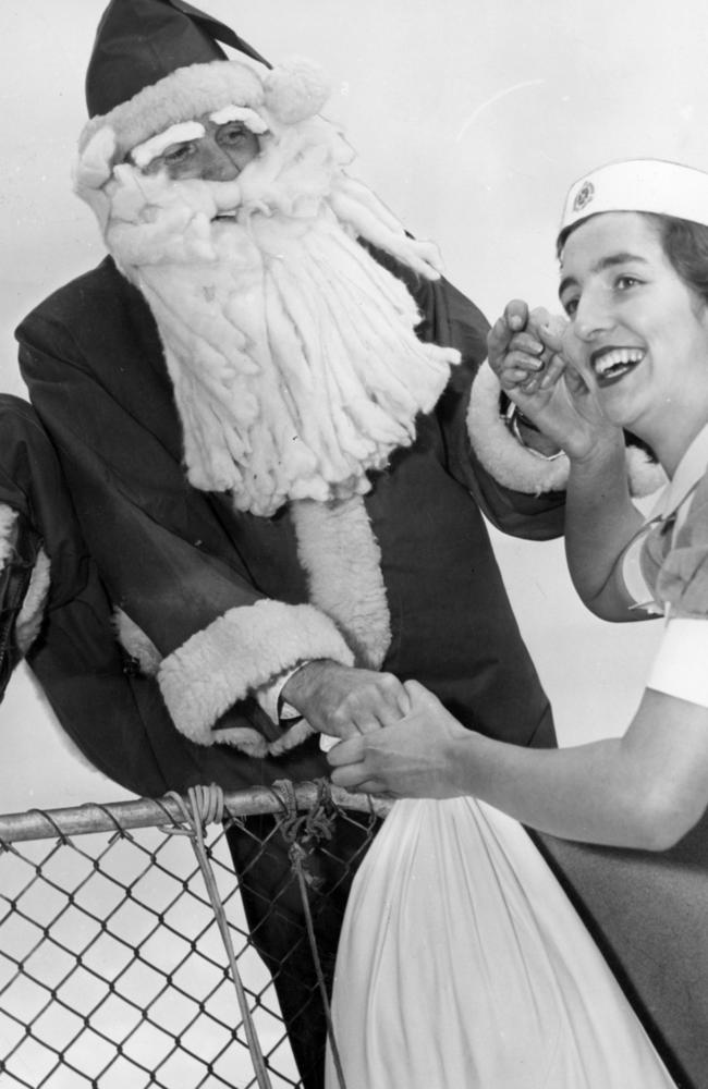 Nurse Barbara Simpson, 17, helps Father Christmas (Alf Kennedy) over the roof as he arrives at the Alfred Hospital in 1955.