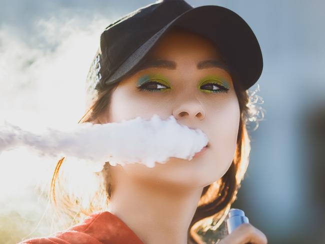 Pretty young asian girl vape popular ecig gadget,vaping device.Happy brunette vaper girl with e-cig.Portrait of smoker female model with electronic cigarette vaporizer.Ejuice vaping with fruit flavor liquid