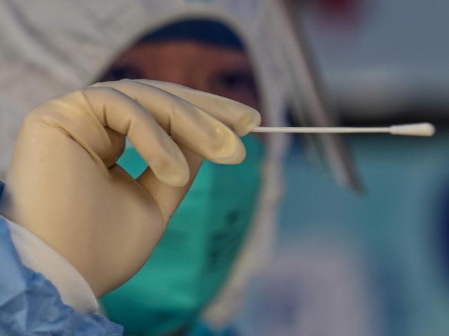 A health worker conducts a swab test for the Covid-19 coronavirus at a residential compound in Shanghai on March 18, 2022. (Photo by Hector RETAMAL / AFP)