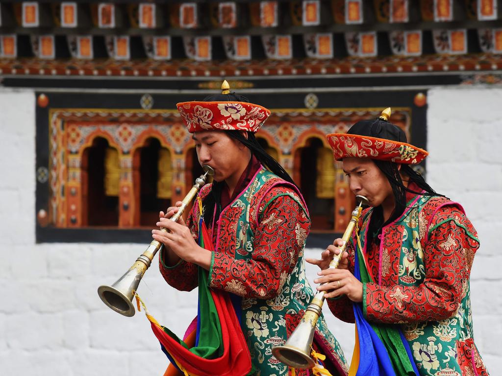 Buddhist monks belonging to a monastery inside the Tashichho Dzong blow into their ceremonial flutes as they escort the national flag after it was lowered from its pole in front of the office of the King of Bhutan Jigme Khesar Namgyel Wangchuck on April 13, 2016. Picture: AFP