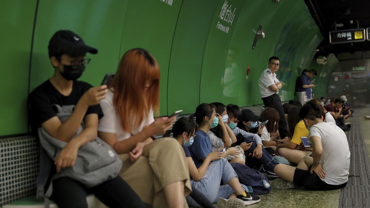 A man in a white uniform crosses his arms as protesters sit on a platform at Fortress Hill MTR underground station in Hong Kong. Picture: AP