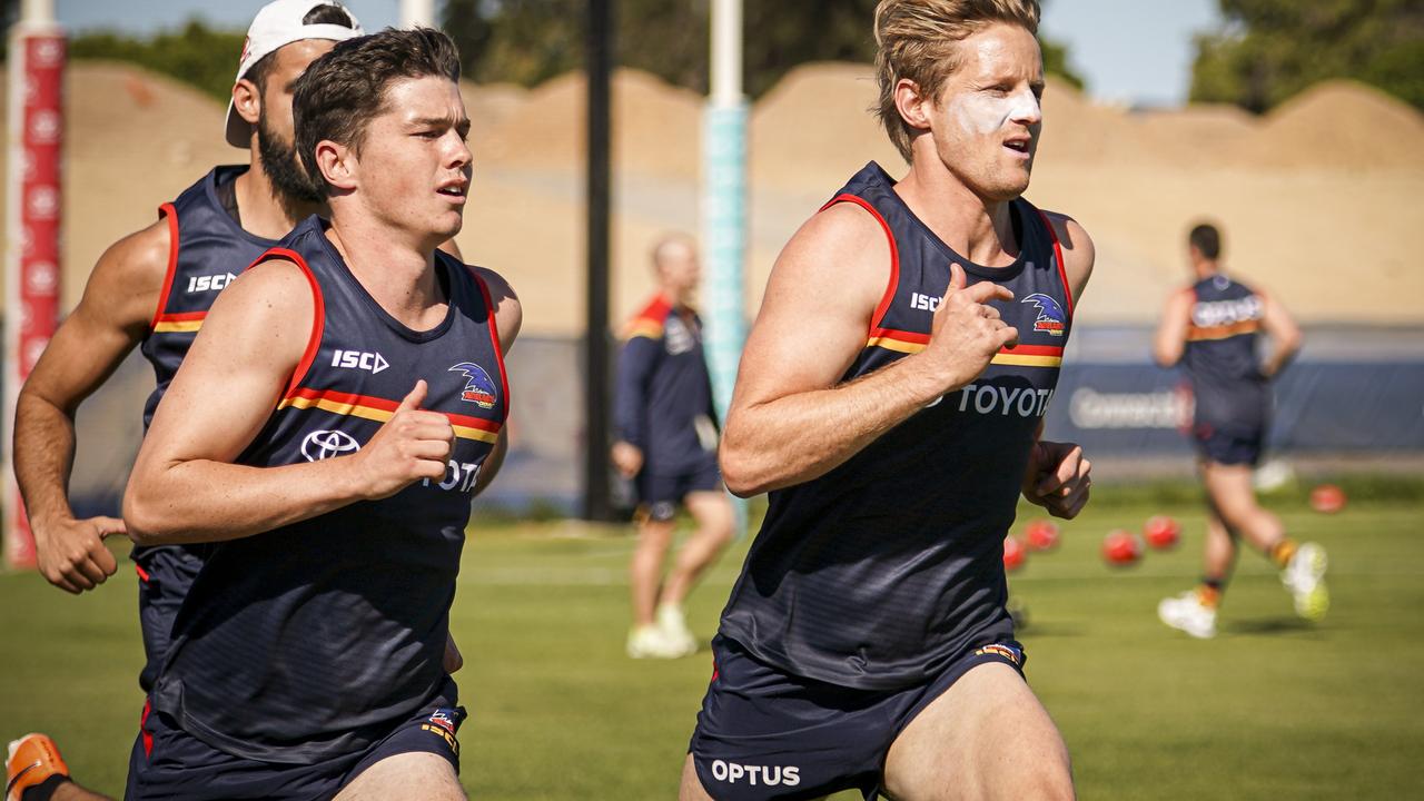 Ned McHenry (left) runs with Crows skipper Rory Sloane.