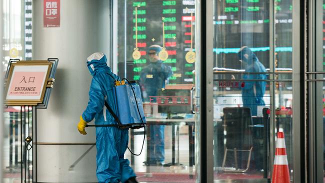 A medical worker sprays antiseptic outside of the front gate of the Shanghai Stock Exchange building. Picture: Getty Images