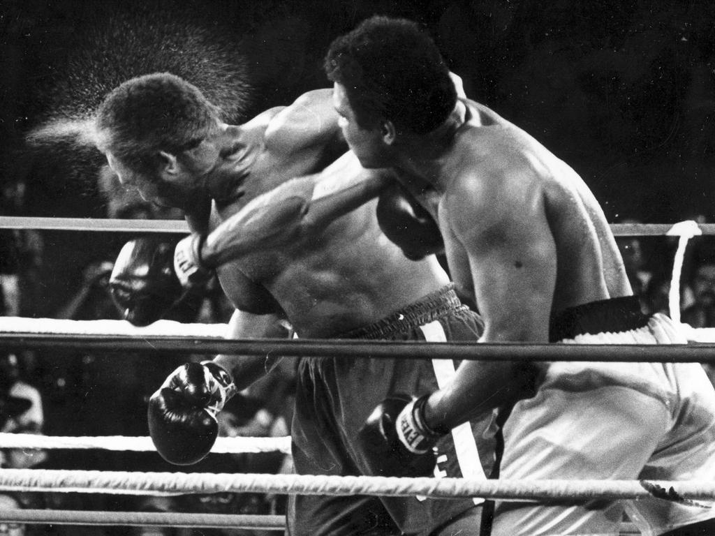 October 30, 1974: Defending heavyweight champion George Foreman takes a savage right from Ali during the famous Rumble in the Jungle fight in Zaire.