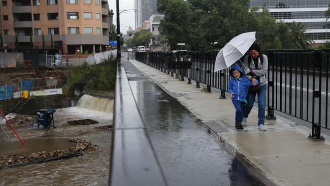 Residents shelter from the drizzle as Parramatta Weir swells behind them. Heavy rain is set to hit this afternoon, increasing on Saturday. Picture: David Swift